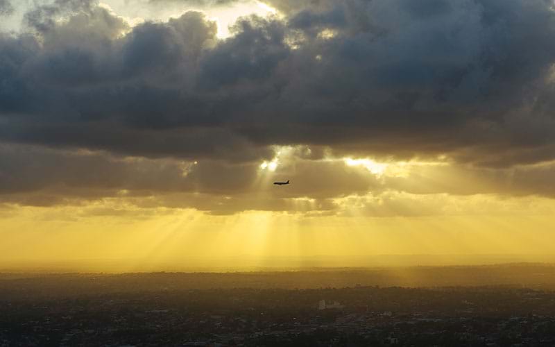 Airplane sillhouetted by light shining through clouds