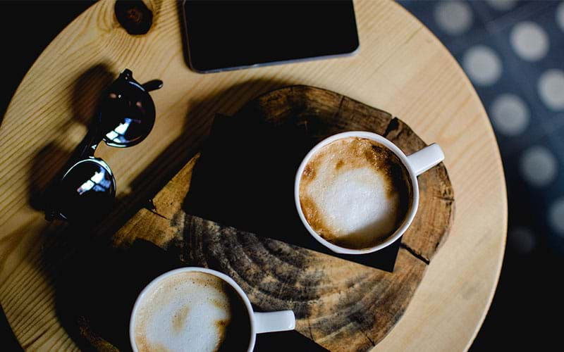 Two lattes sitting on wood table