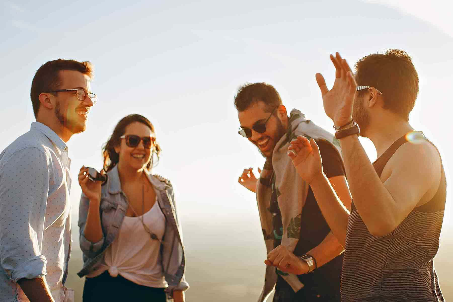 Four friends laughing together at sunrise