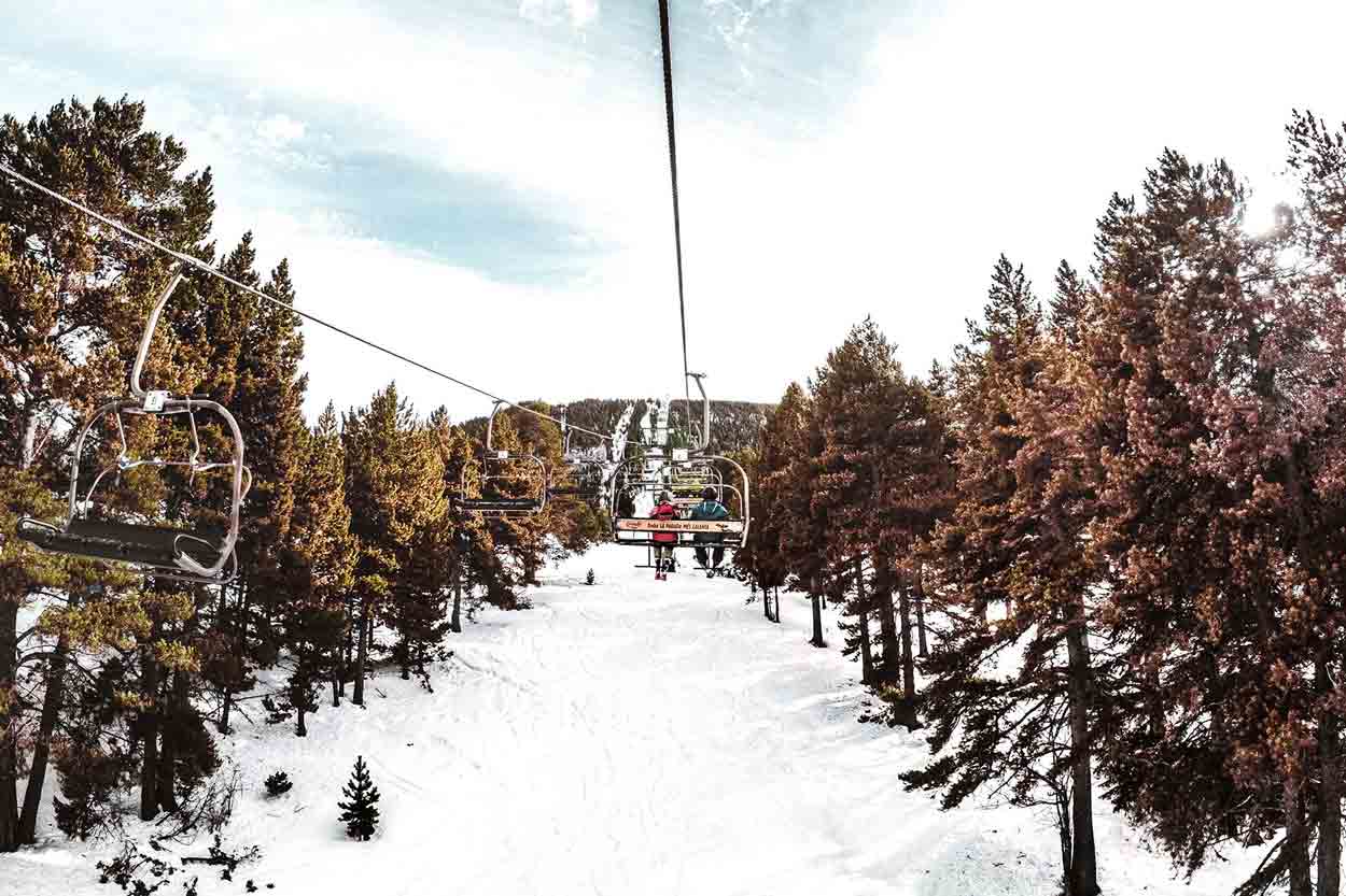 Ski lift over snowy path between trees