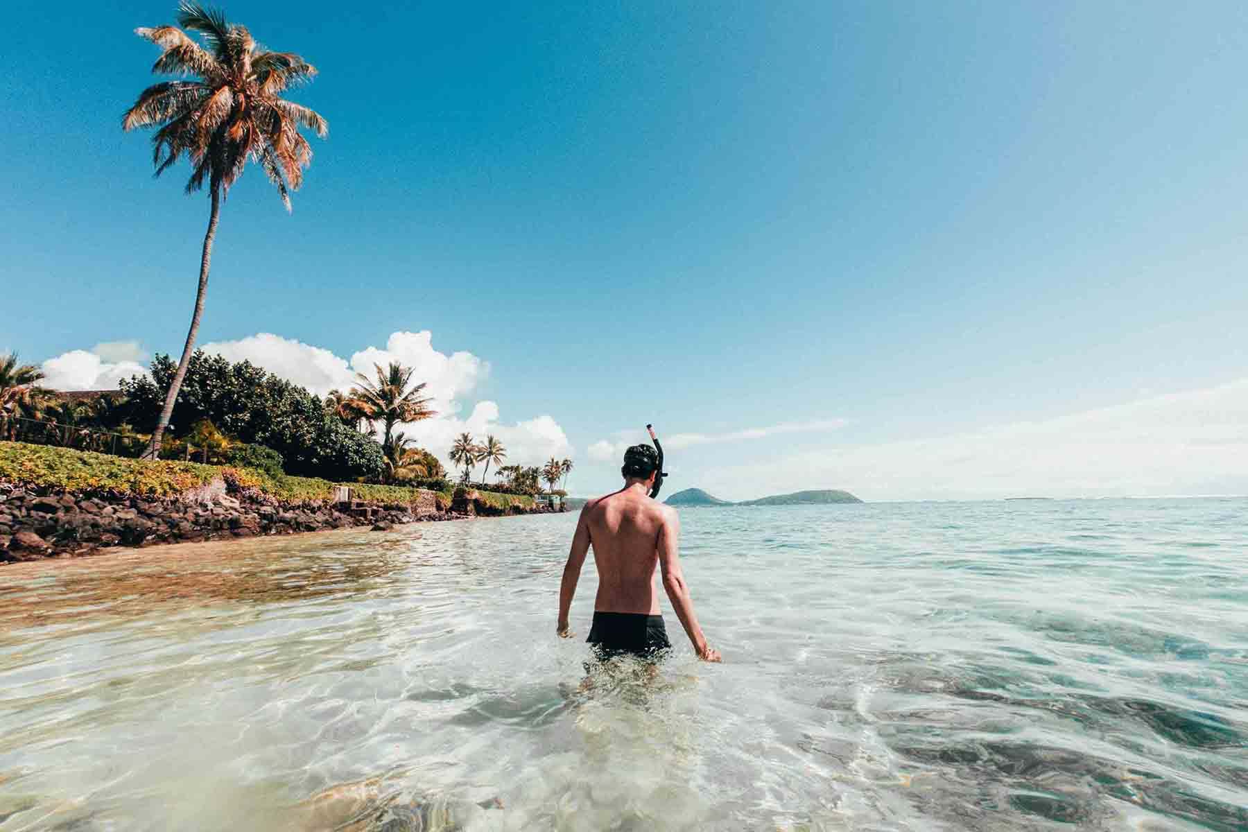 Man wading in shallow water wearing snorkle 
