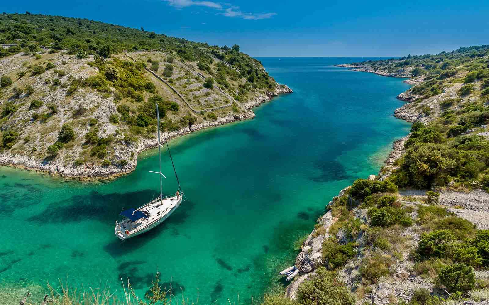 A sailboat sailing through a green river in Croatia