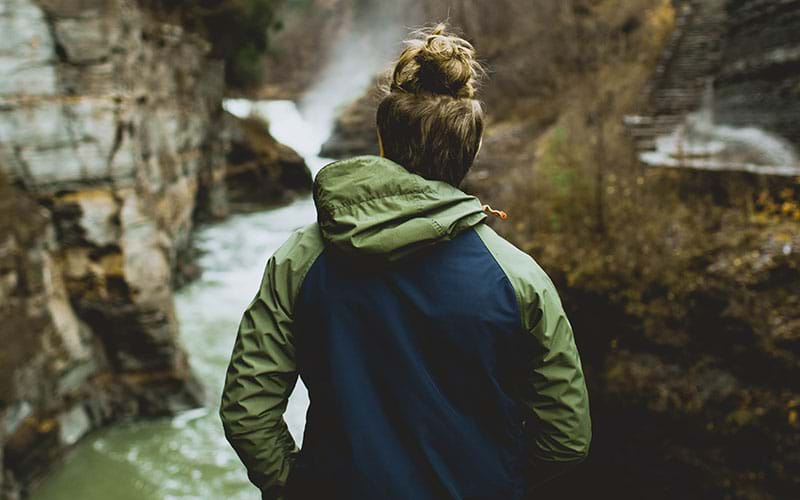 Woman in jacket looking at river rapids