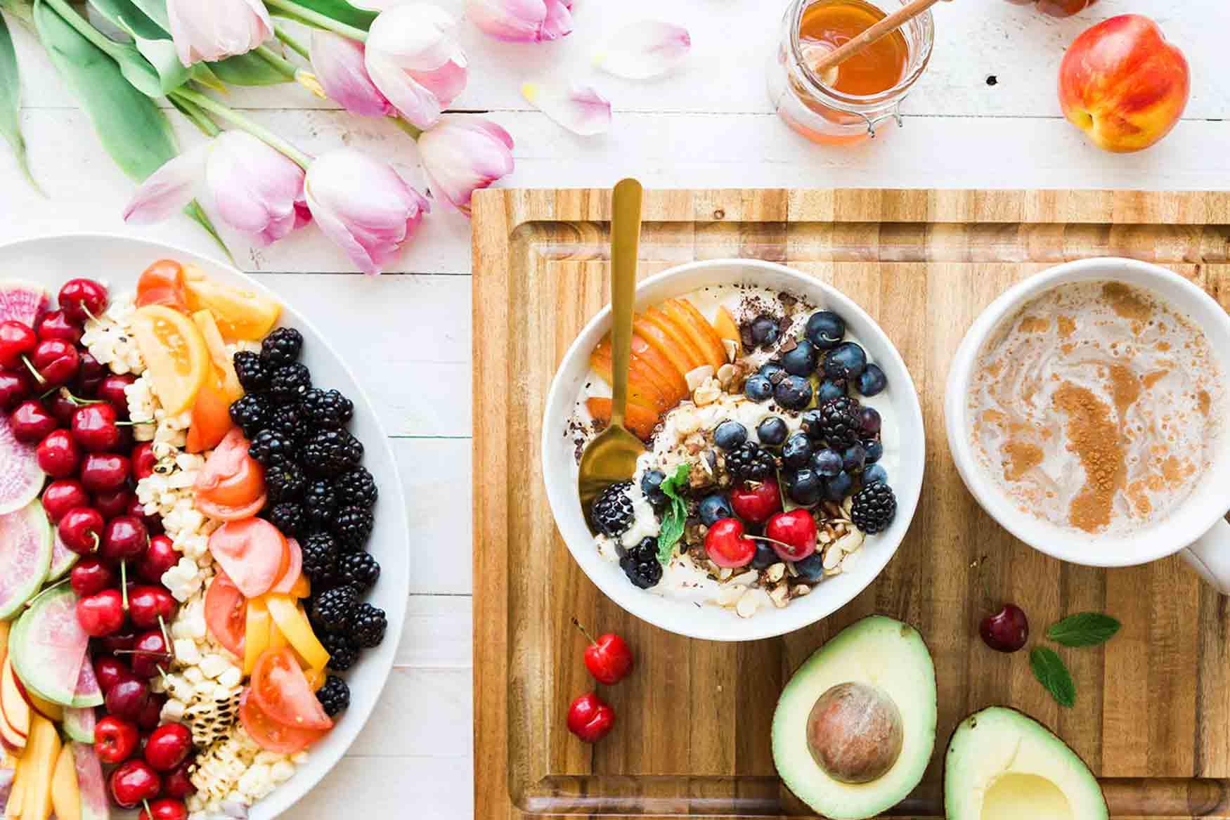 Bowl of oatmeal with fruit next to coffee