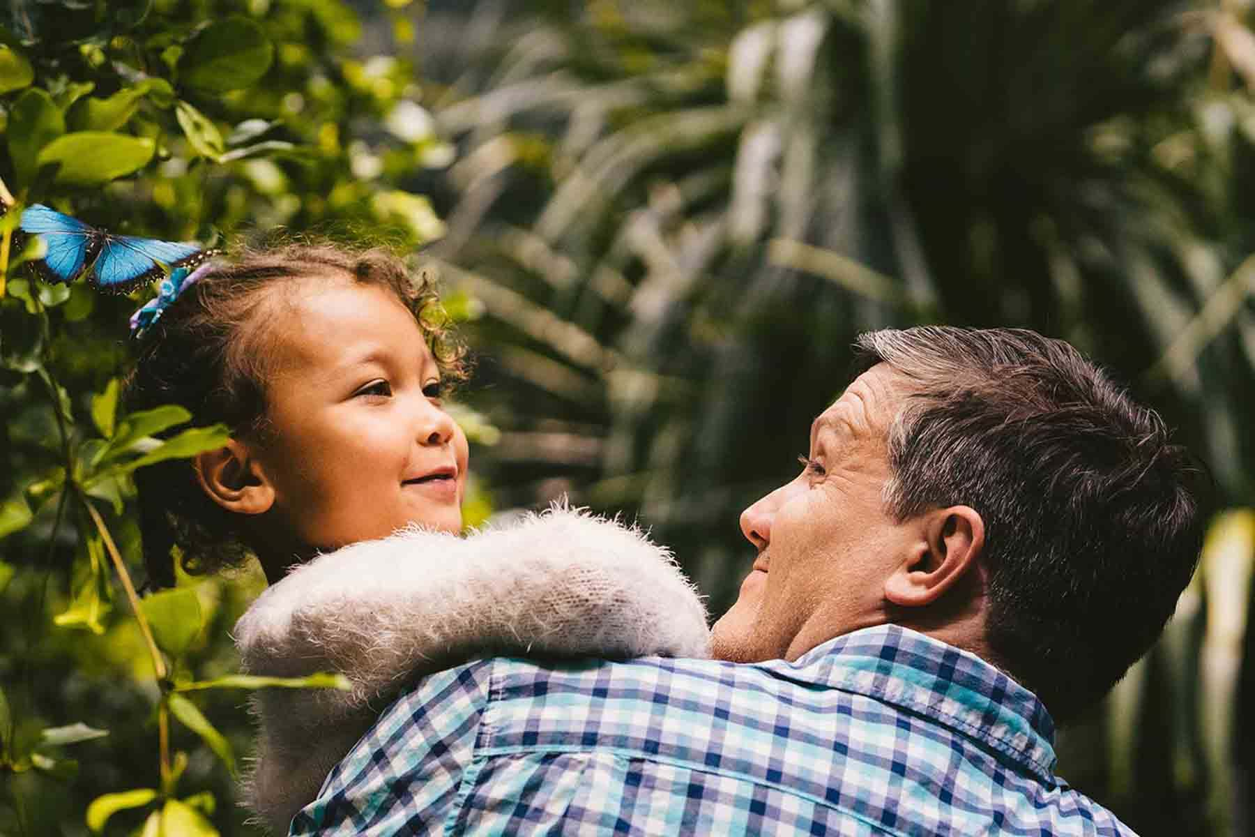 Dad holding child near blue butterfly