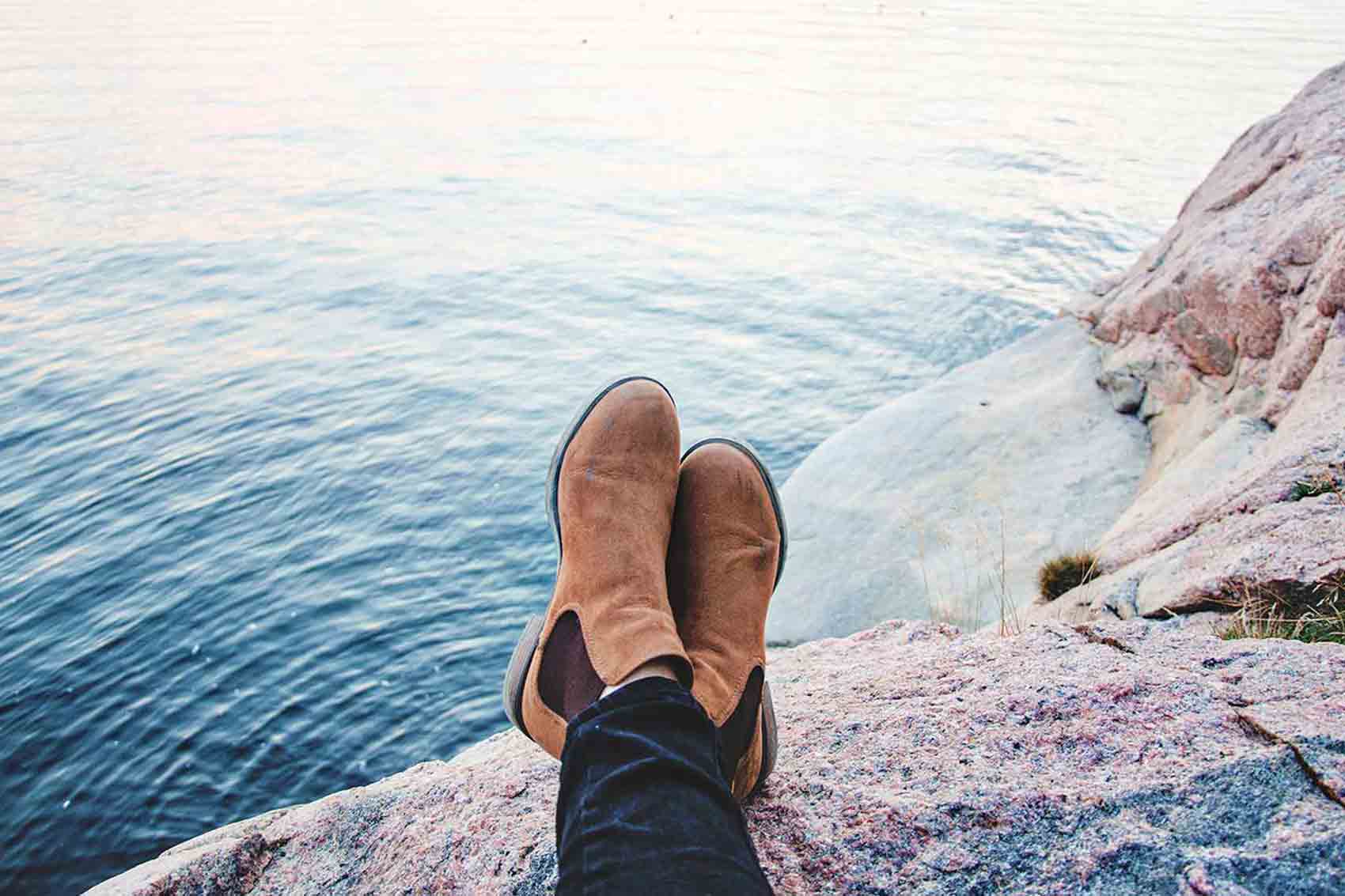 Person sitting on rock with legs crossed near water