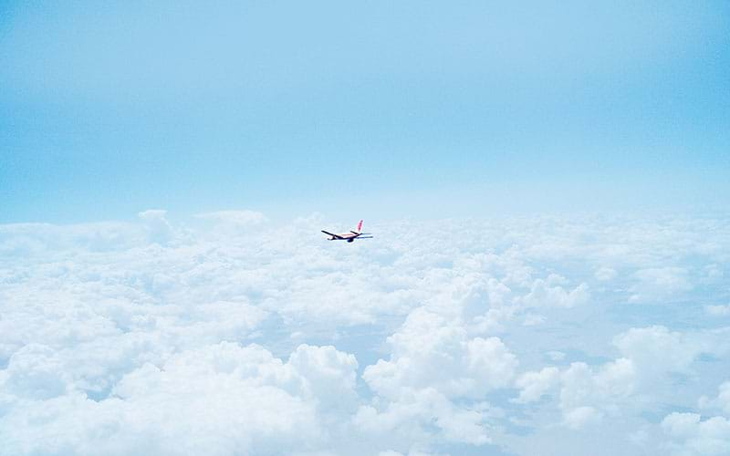 Plane in the distance soaring above the clouds