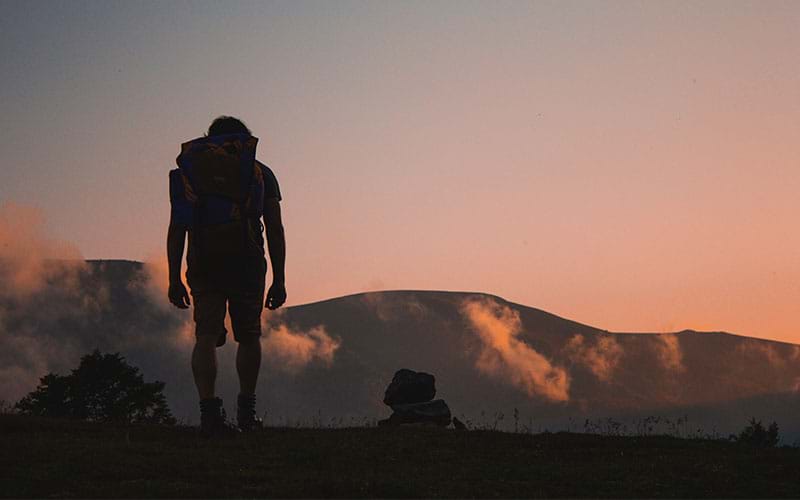 Hiker in the mountains with pink sunset sky