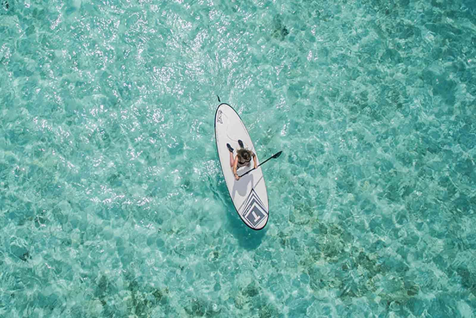 Woman paddleboarding on blue-green water