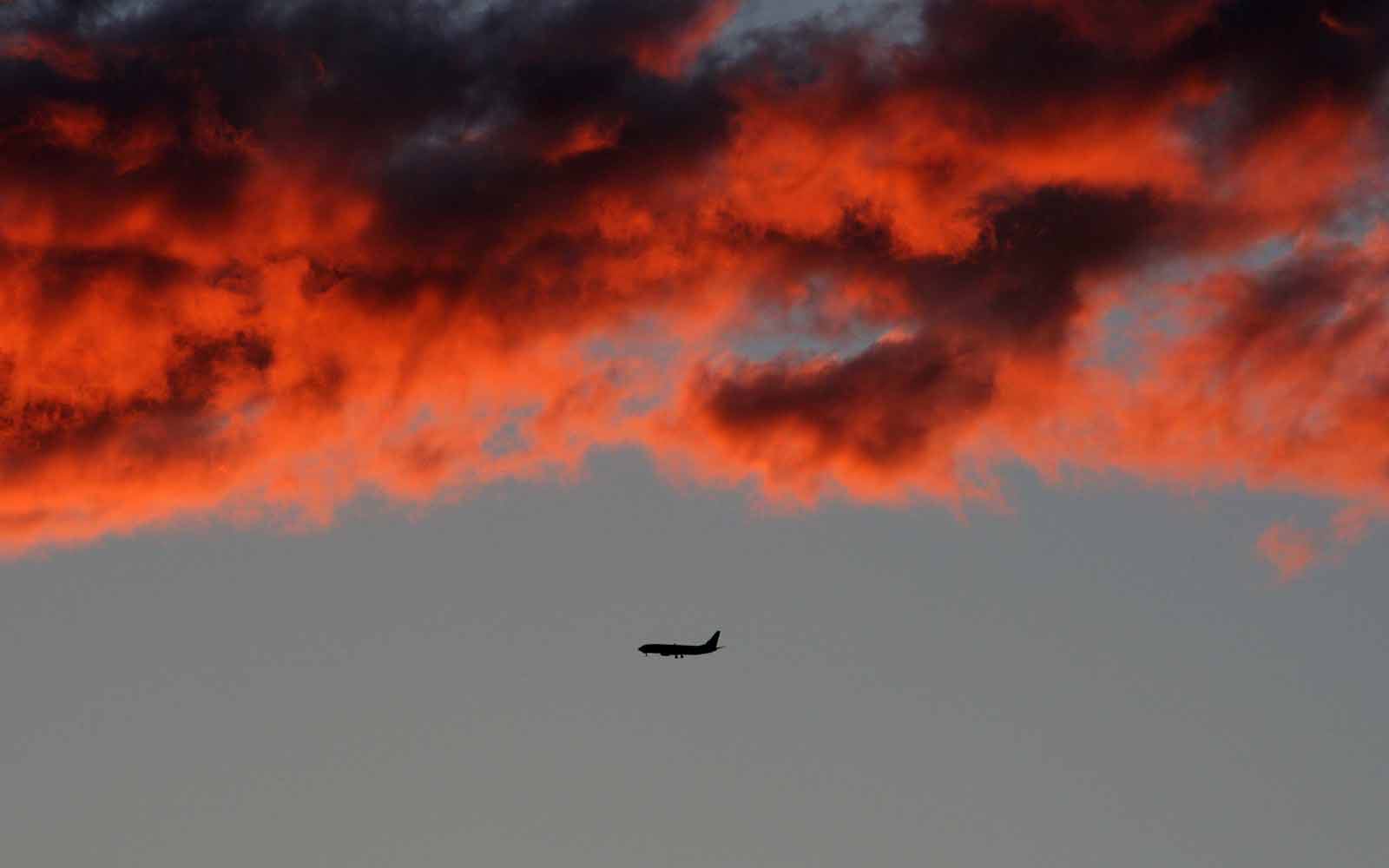 Plane flying under red clouds