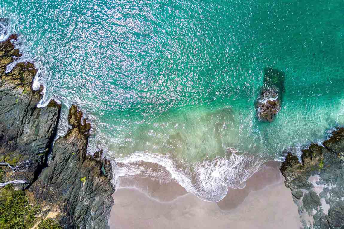 Waves wash up on narrow beach between rocks