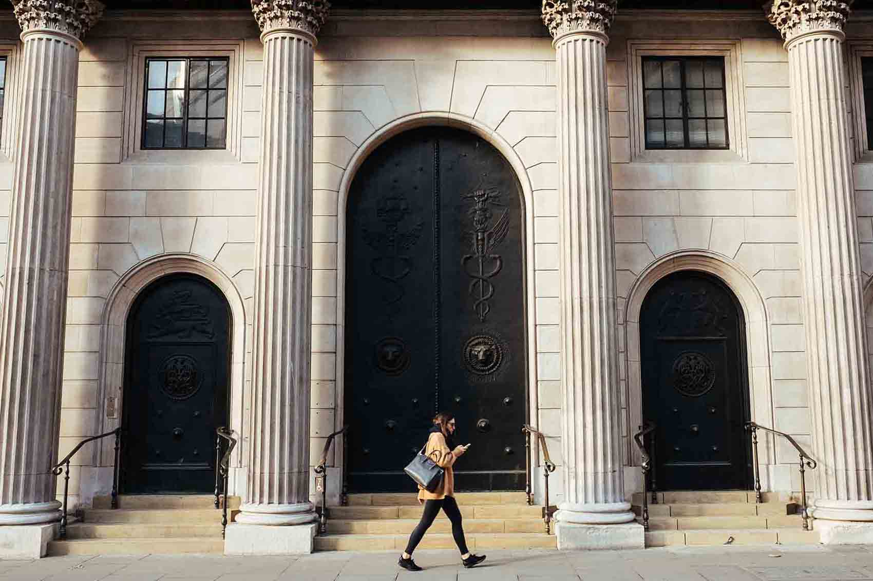 Woman walking past building with columns