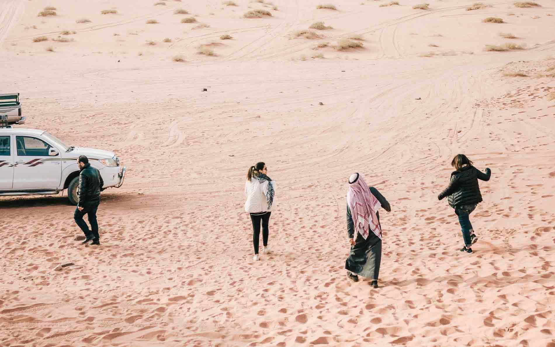 People walking down sand dune in desert