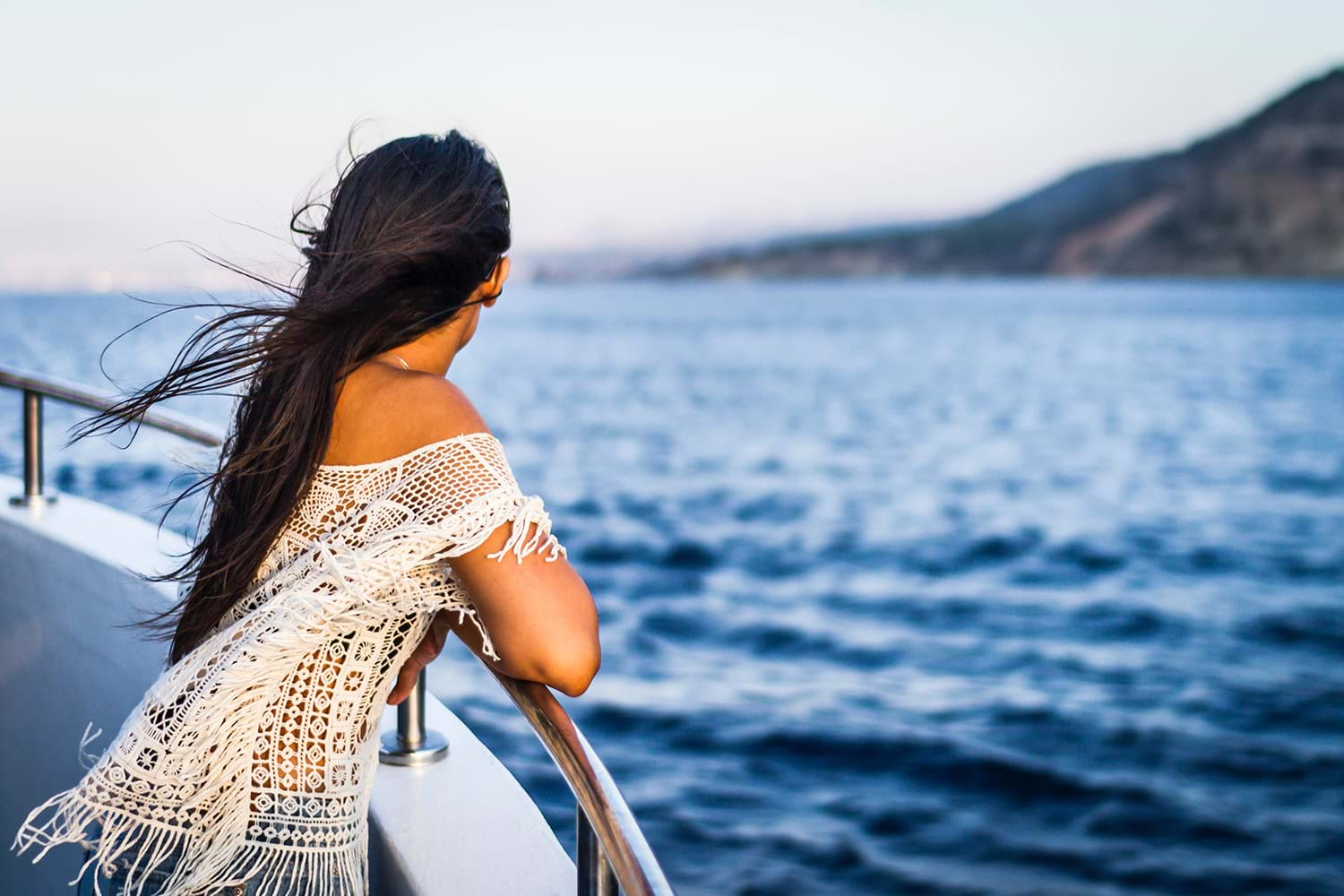 Woman leaning on ship railing while looking at scenery