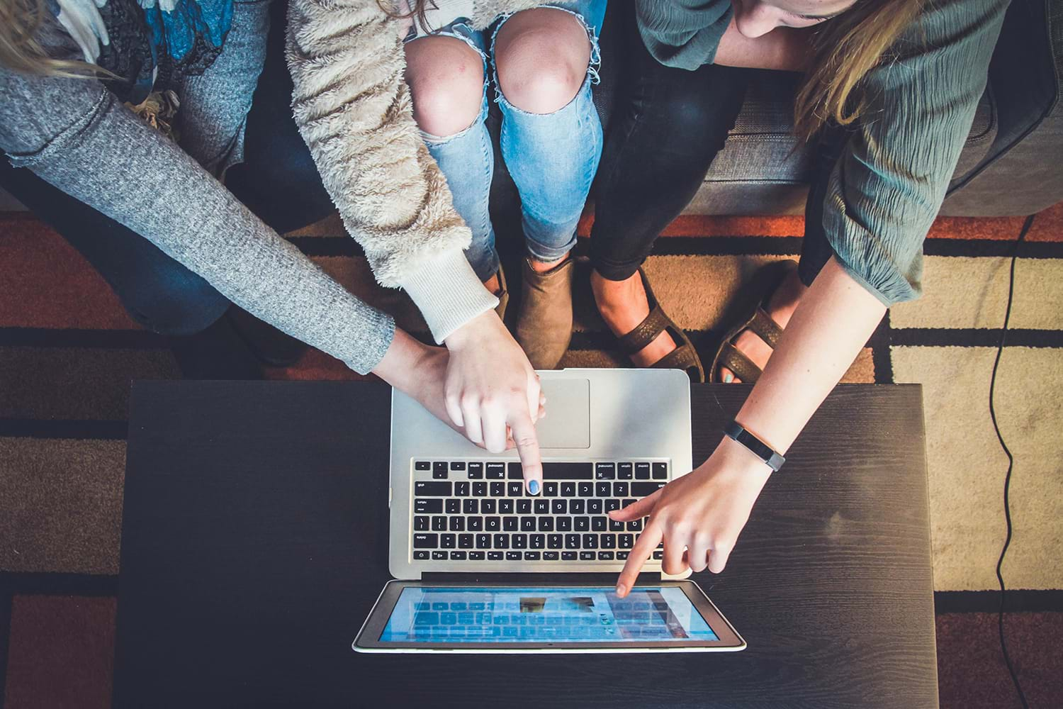 Three women huddling around laptop