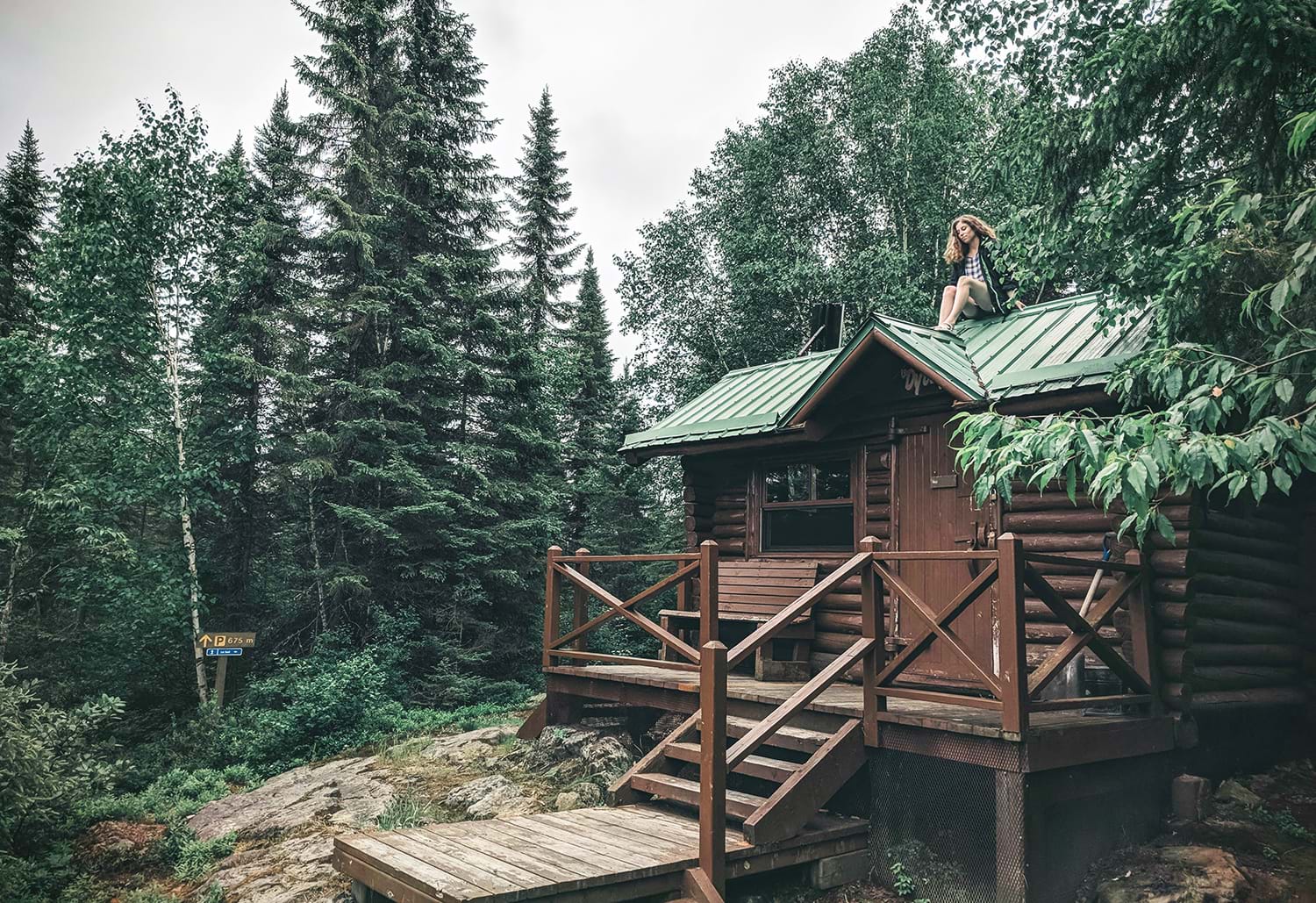 Woman sitting on roof of log cabin