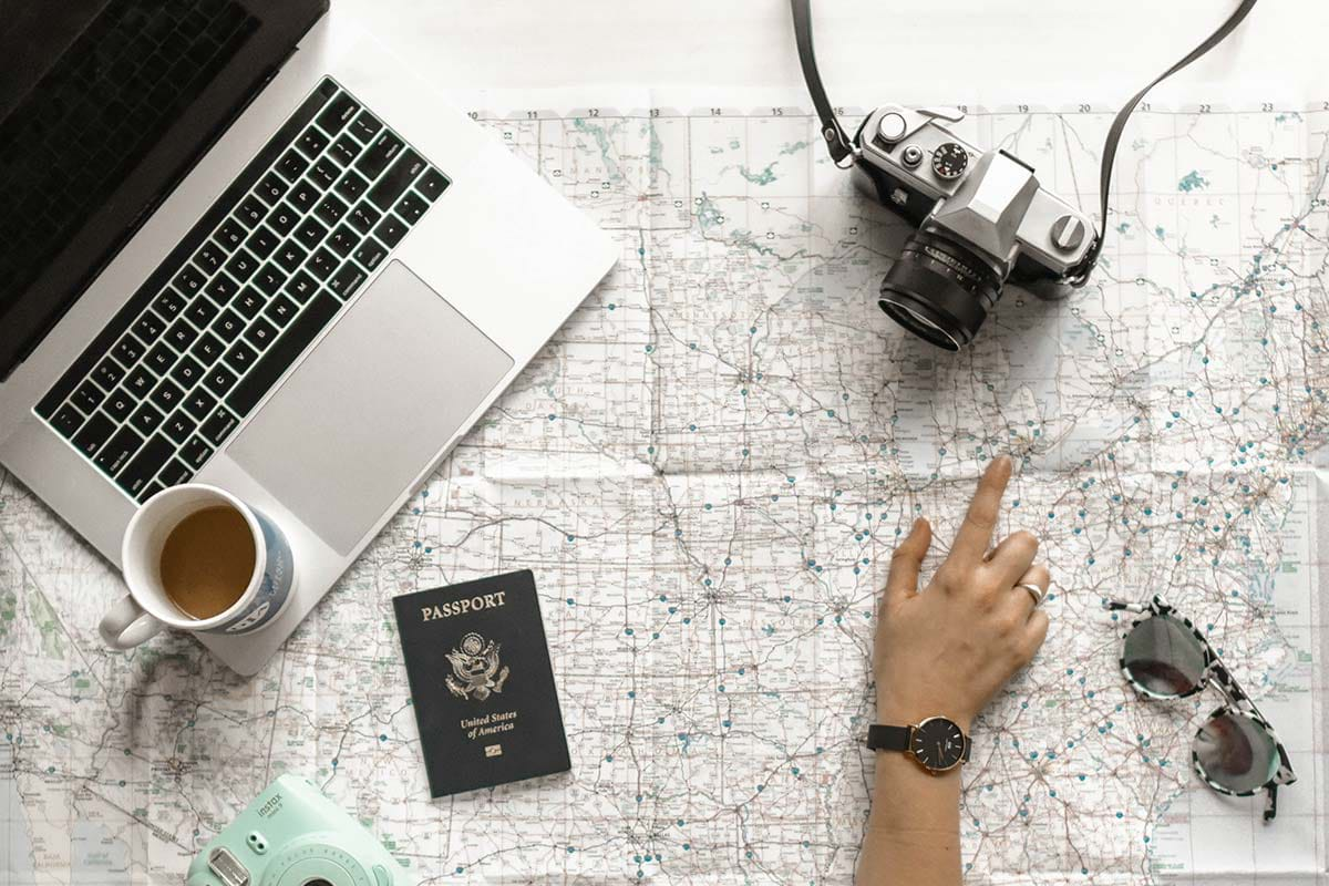 Hand pointing to map with camera and laptop on it