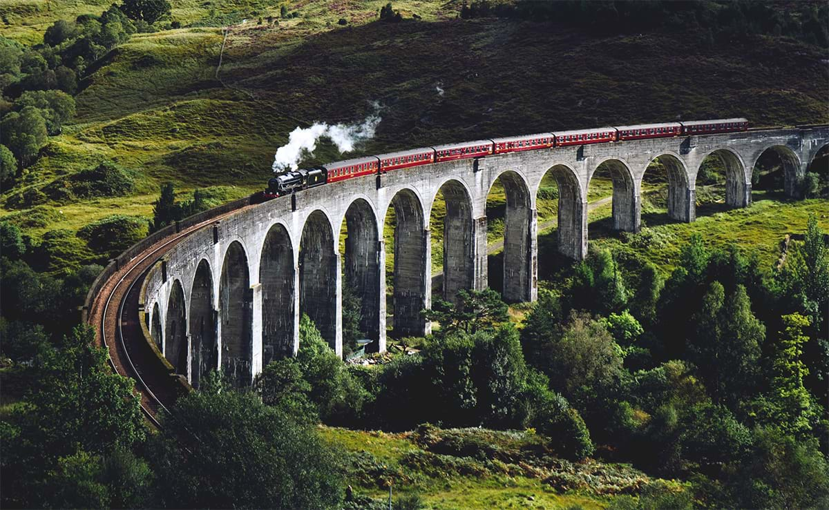 Train traveling along raised track through countryside