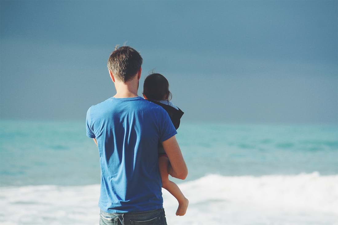 Dad holding child while looking out at water