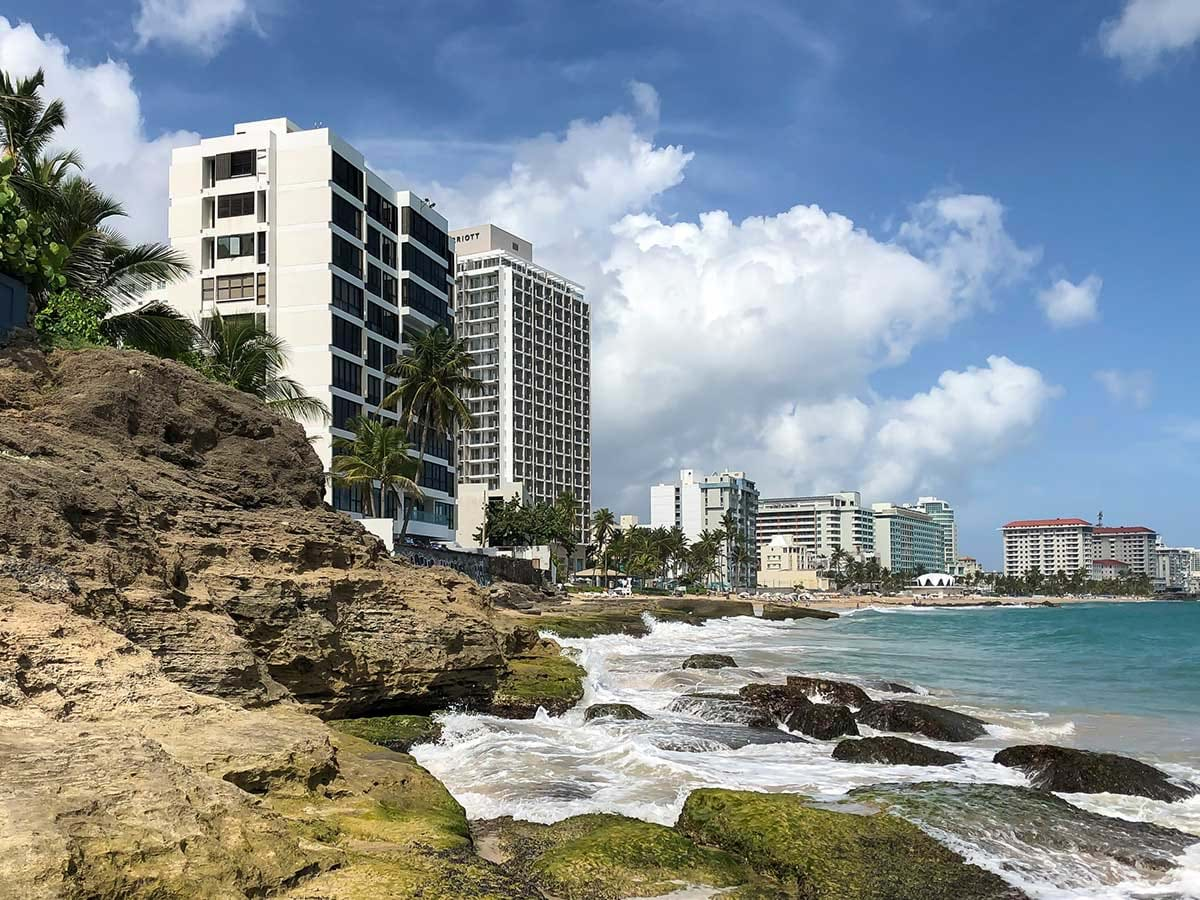 Waves washing up on rocks with buildings in the background