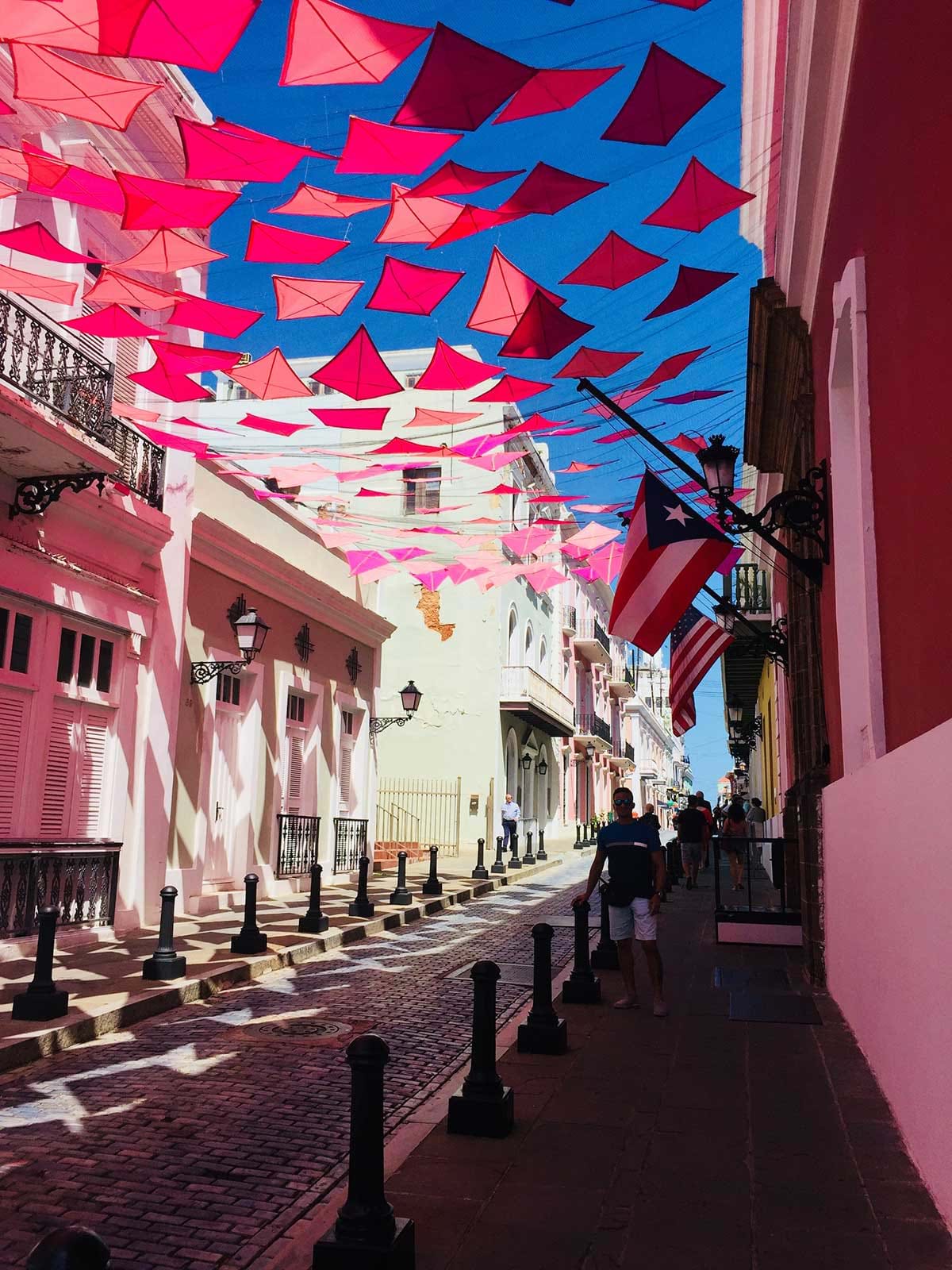 Red and pink flags providing shade over narrow street