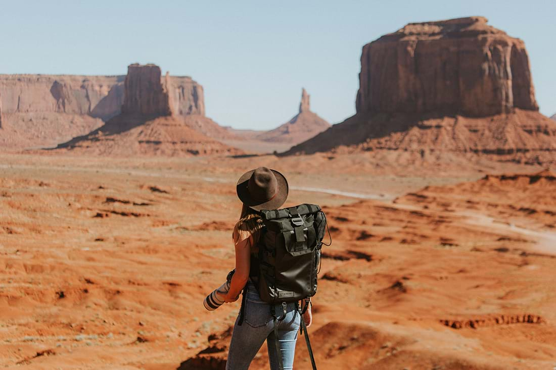 Woman hiking through desert looking at mesas