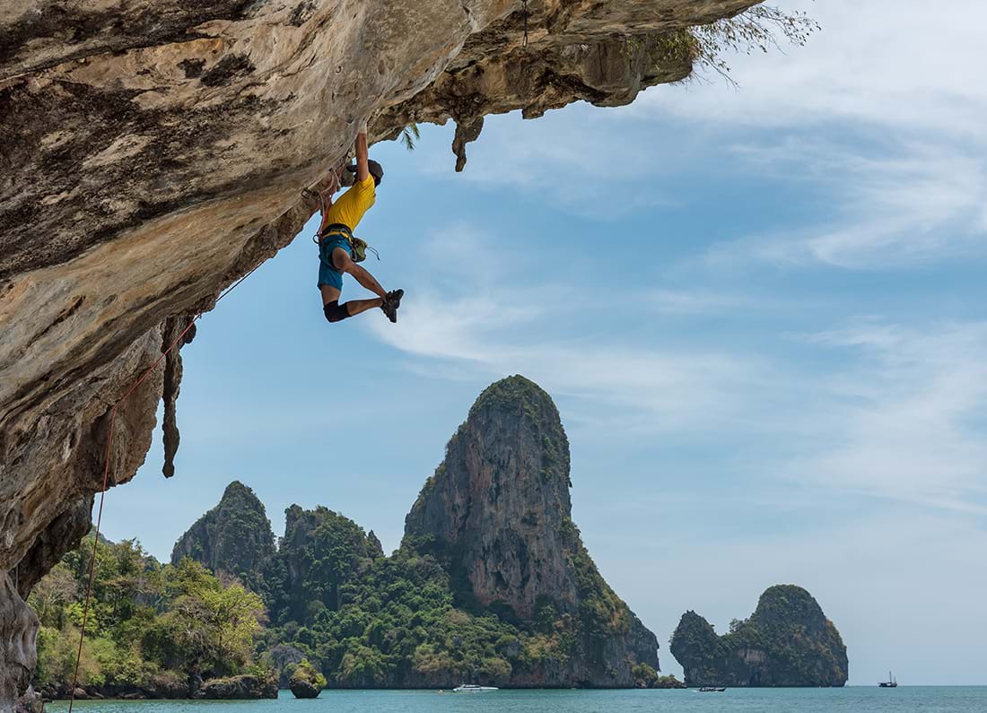 Rock climber scaling underside of cliff