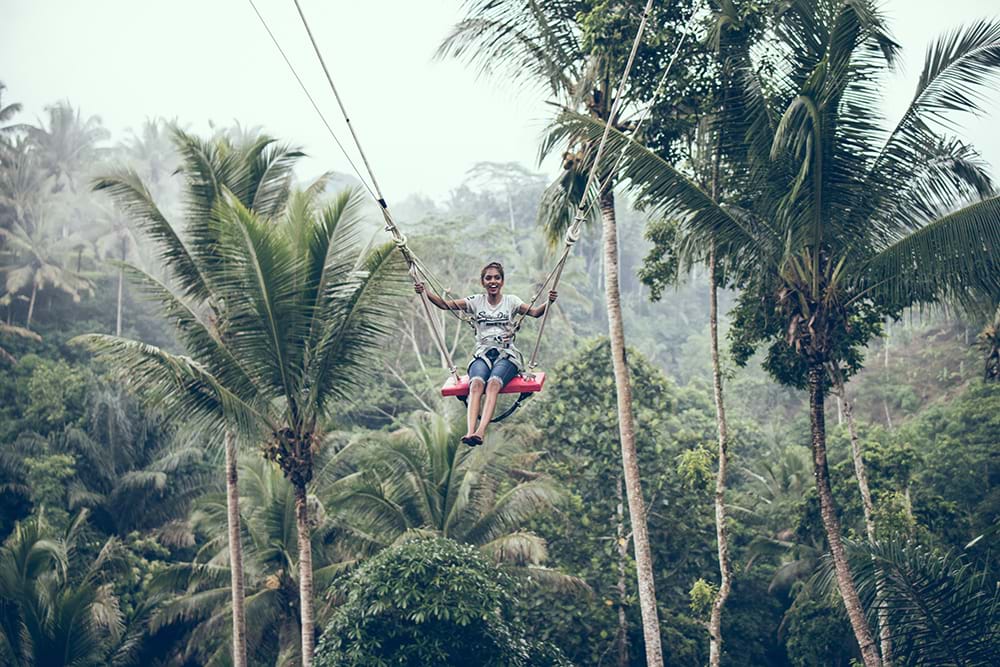 Woman riding massive swing in jungle