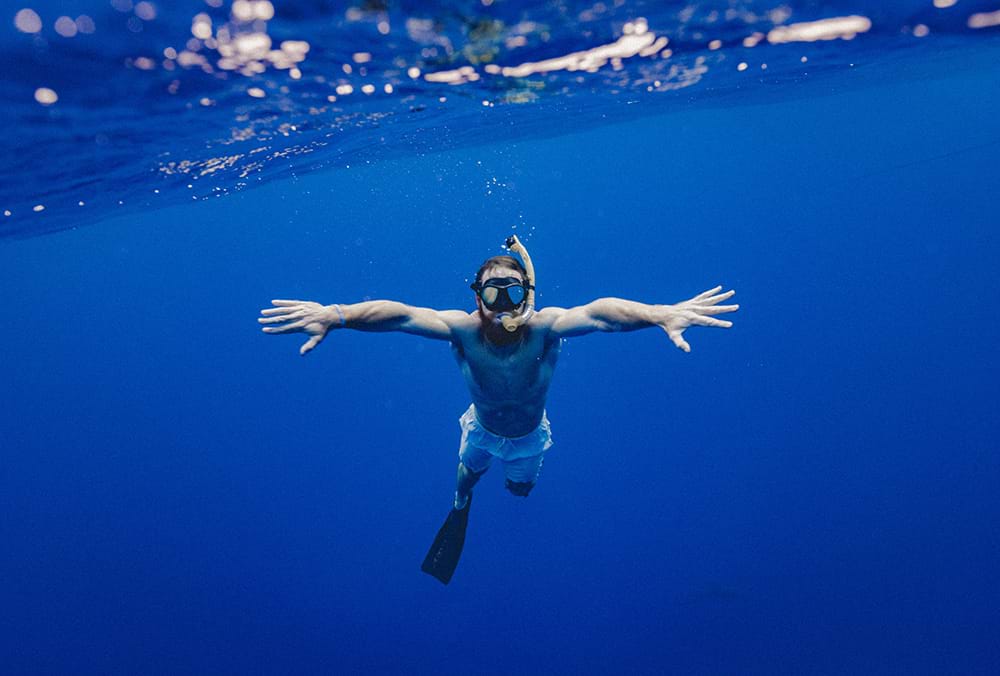 Man snorkling in deep blue water