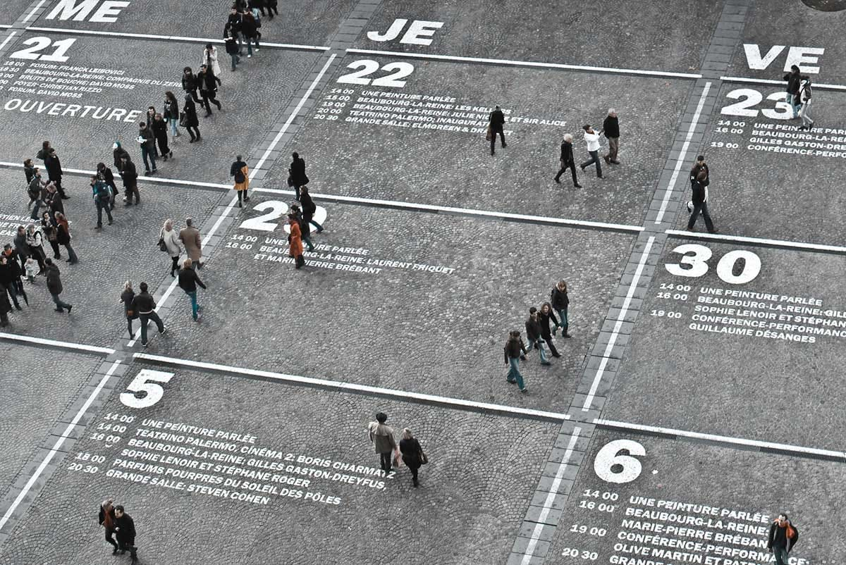 People walk across numbered rectangular segments in road