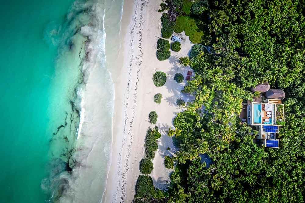 Aerial view of luxury house next to tropical beach