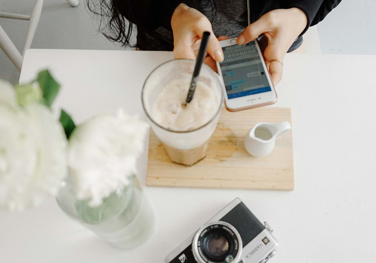 Woman texting while sitting at table with coffee