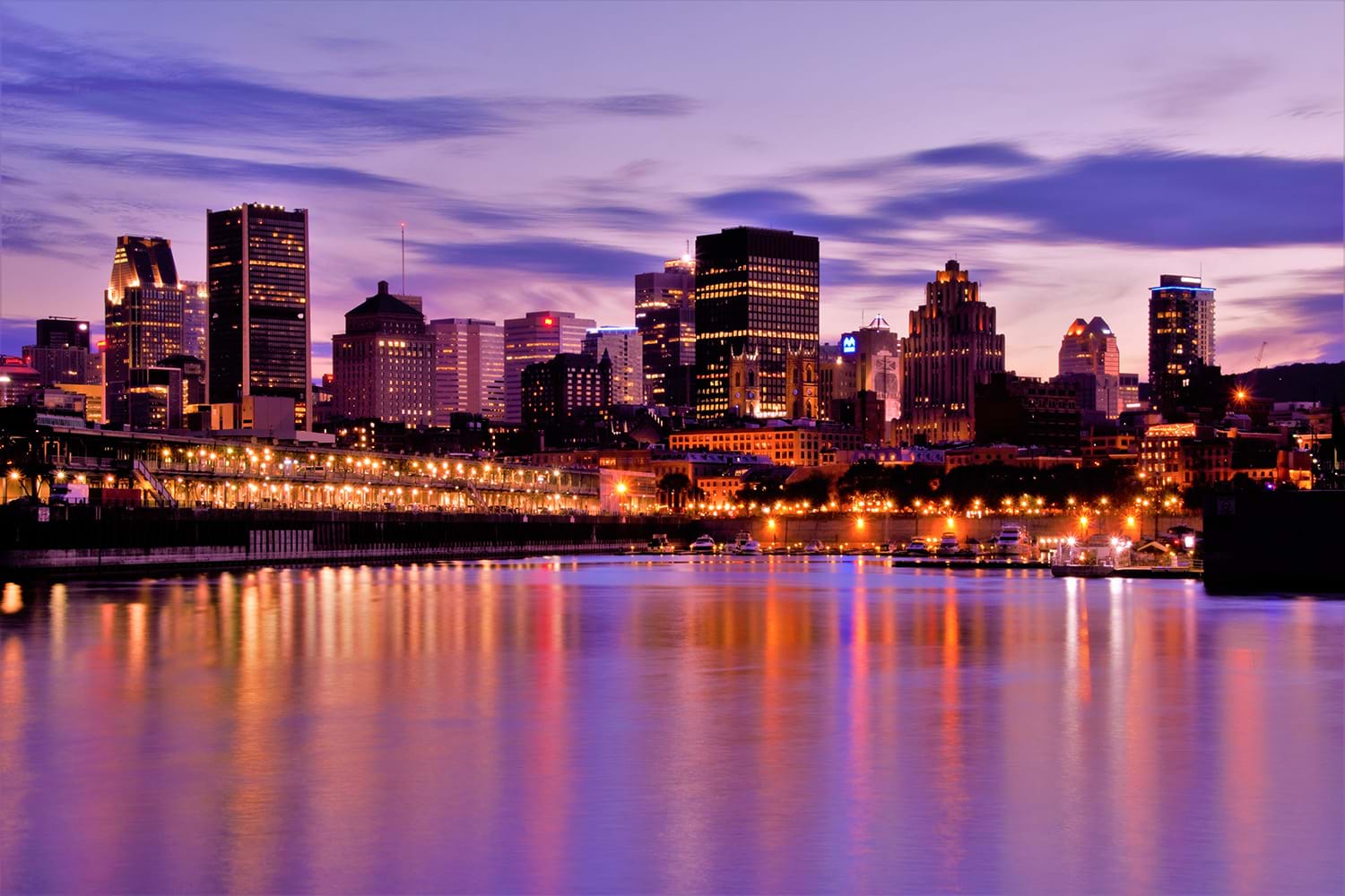 City skyline reflecting violet and orange light into water
