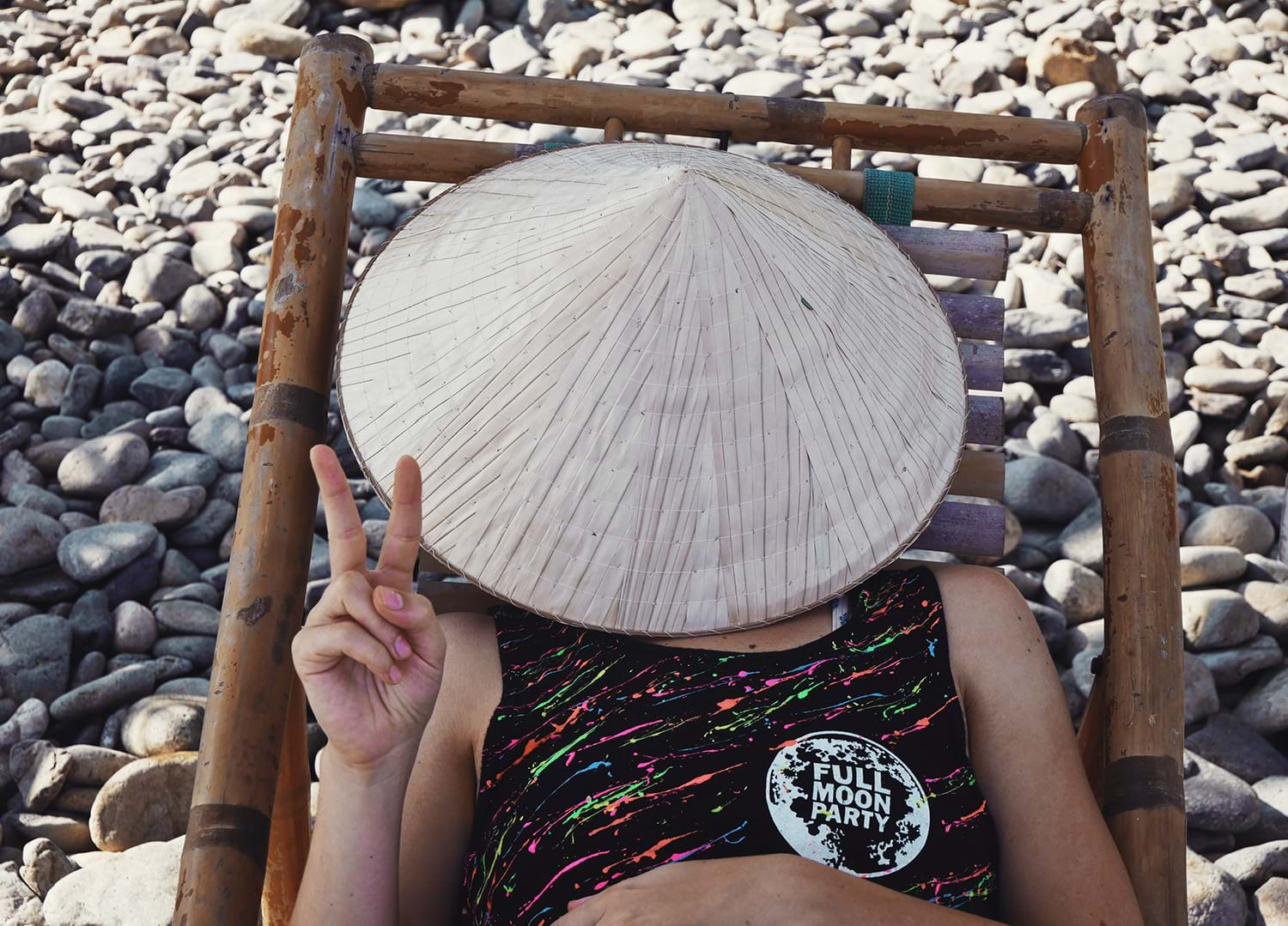 Person lounging in beach chair with hat over face