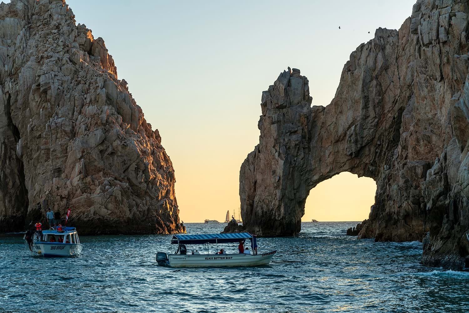 Small boats near rock formations out in the water