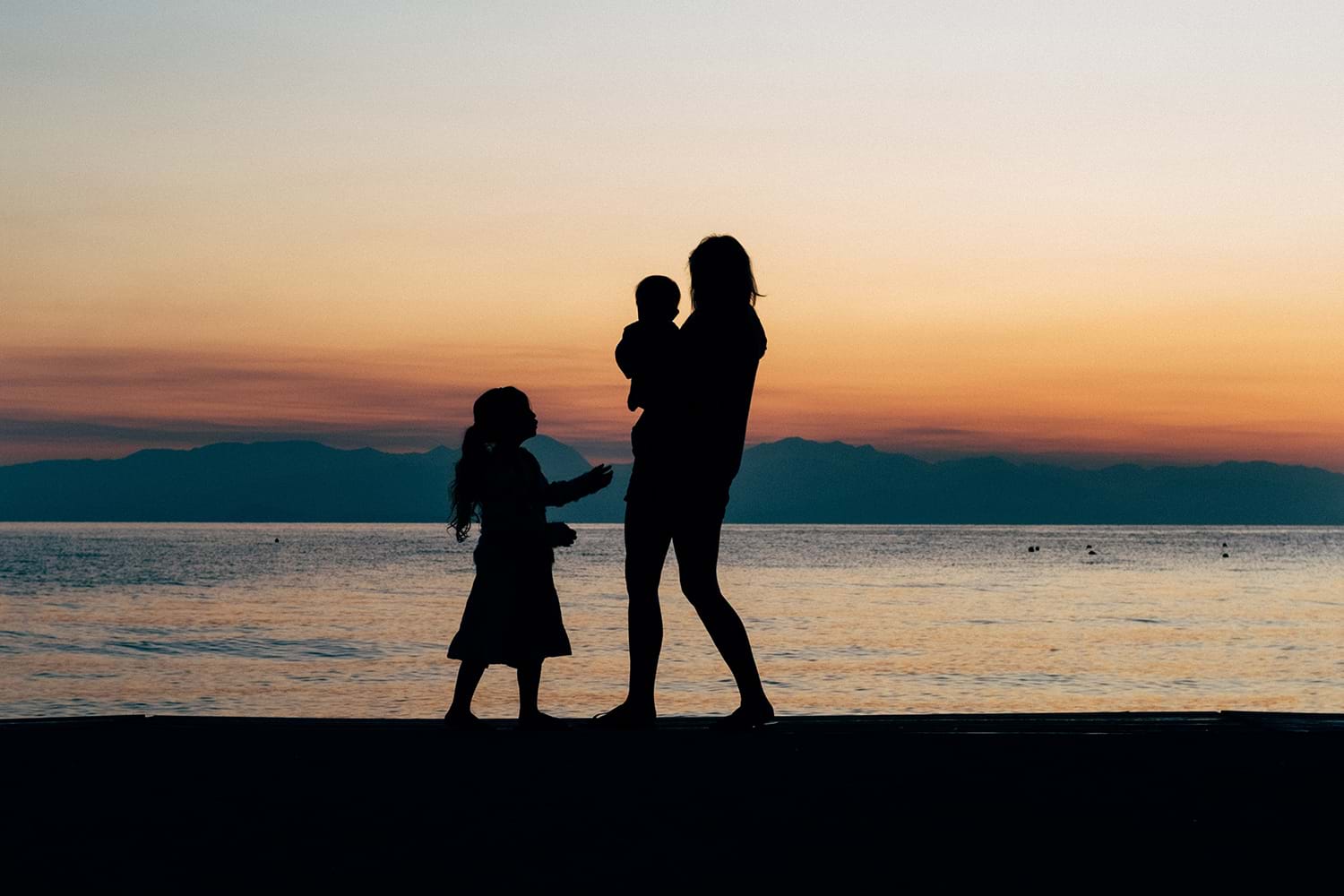 Family silhouetted in the sunset on beach