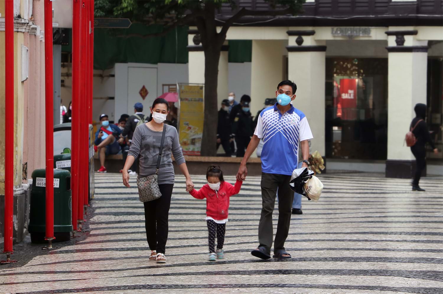 Parents walking with child, all wearing masks