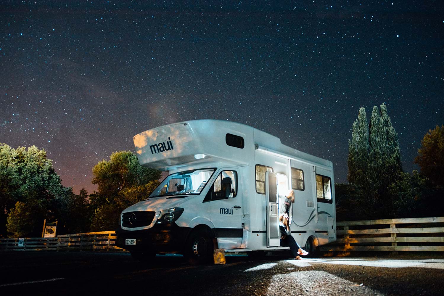 Camper parked in lot with starry sky above