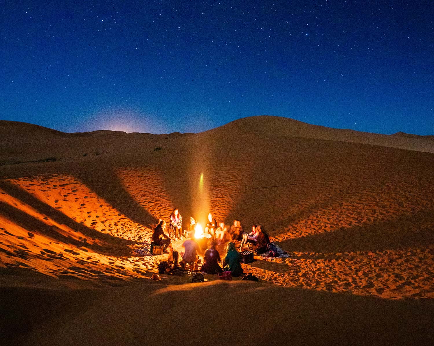 Group sitting around bonfire in desert 