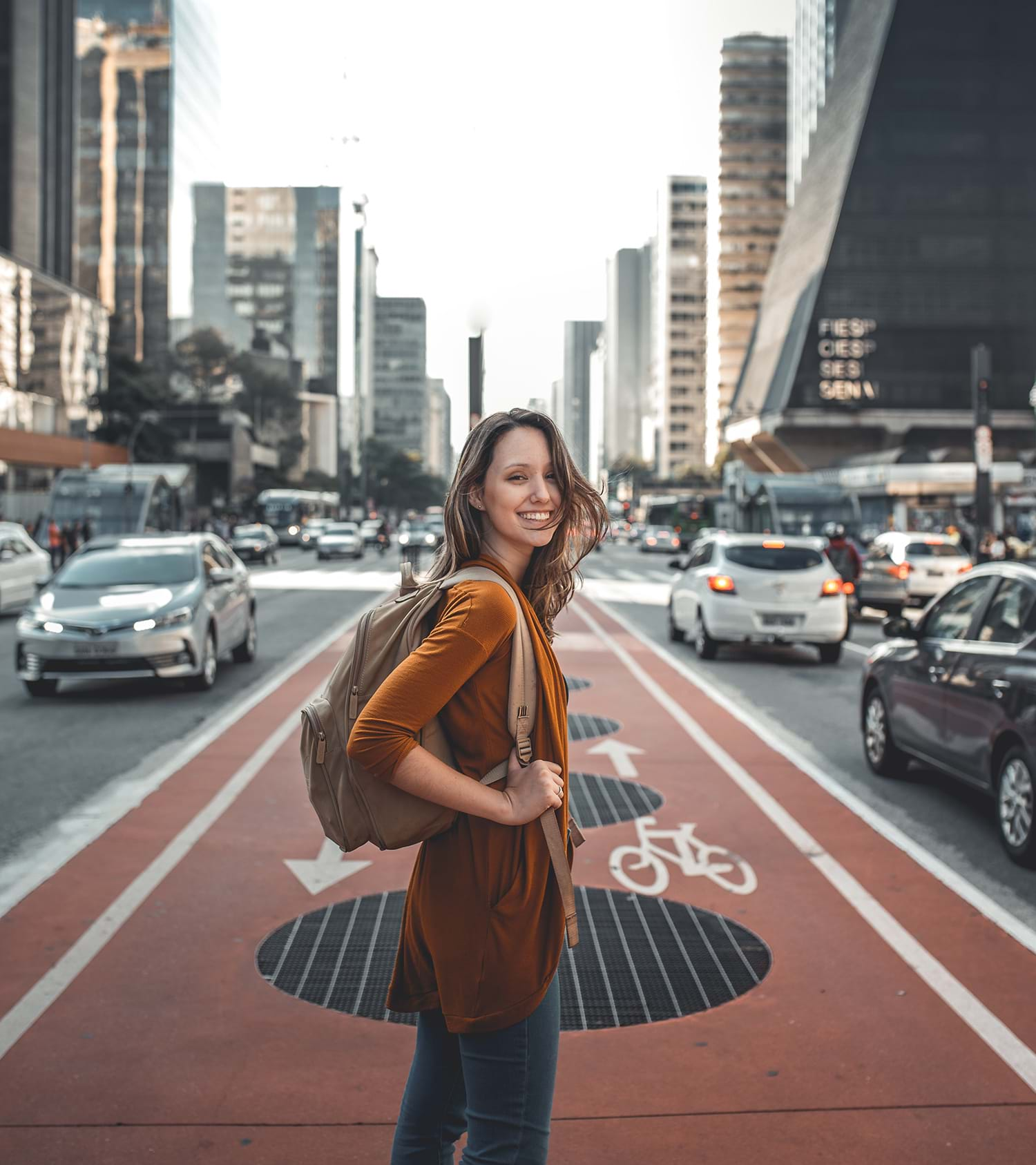 Young woman smiling and walking in bike lane on city street