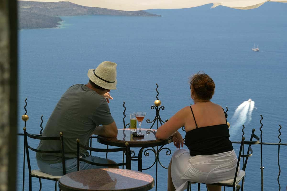 Couple having drinks on balconey looking out over water