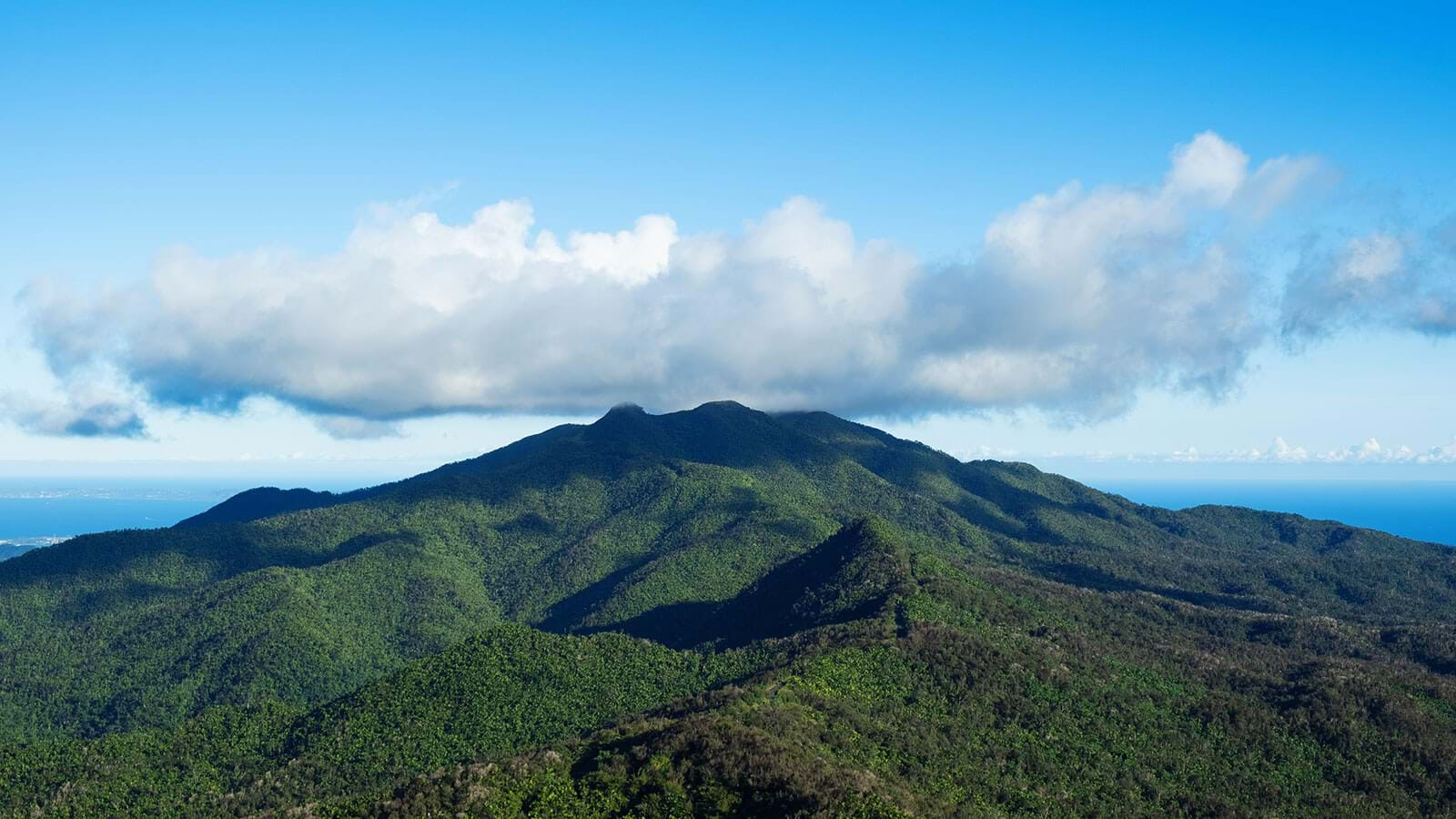 Clouds over forest covered mountain