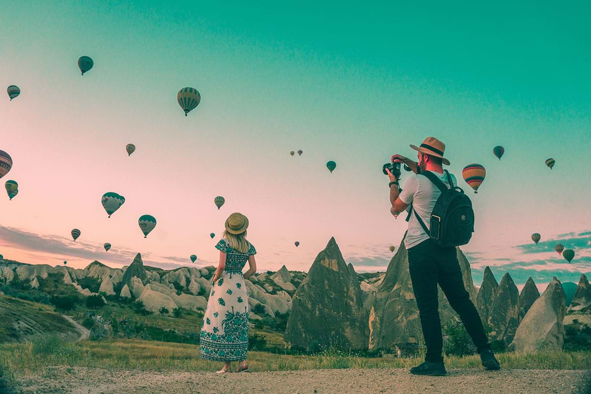 Couple taking pictures of hot air balloons in the sky