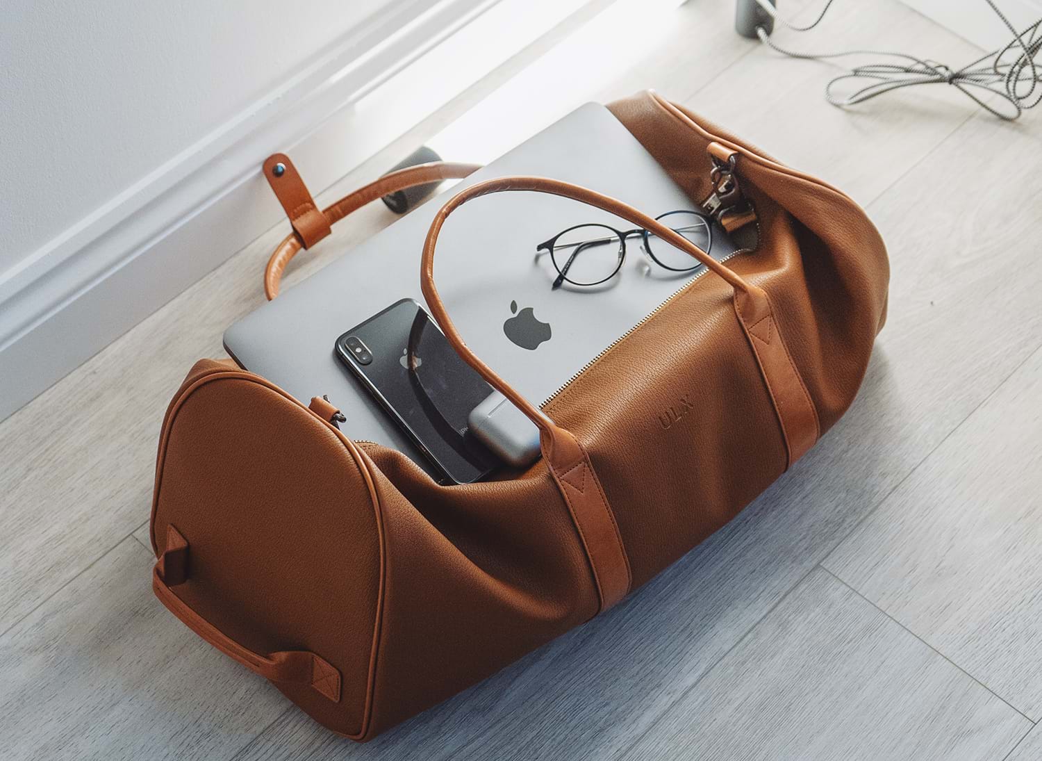 Brown leather bag packed with laptop, phone, and glasses