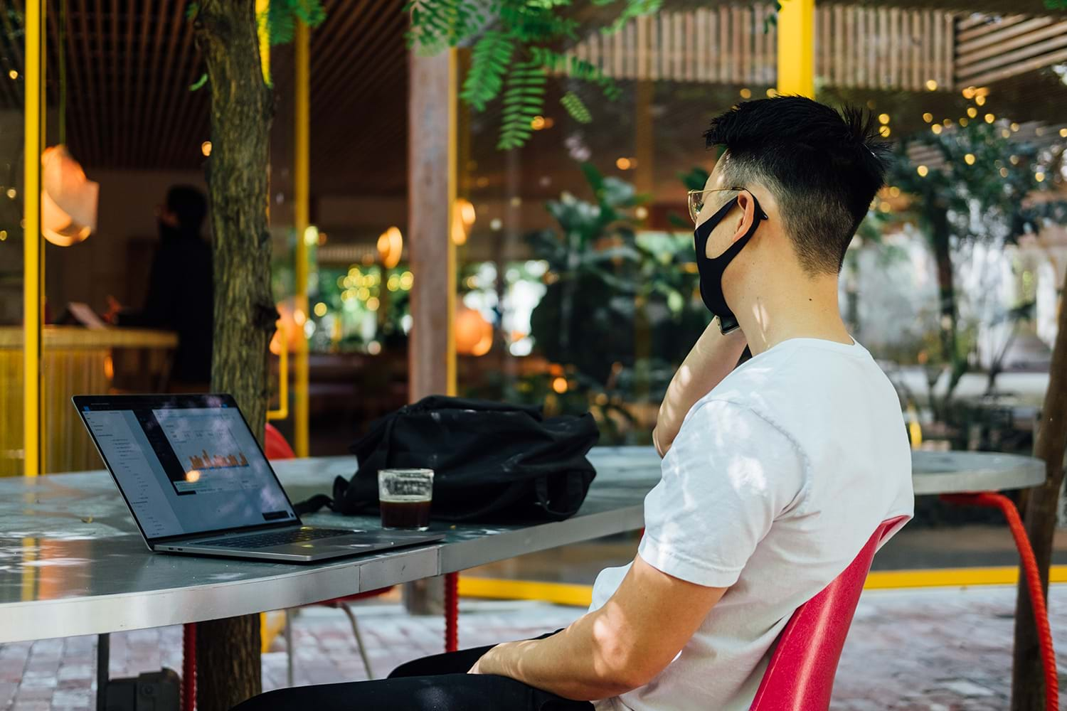 Young man in mask working on laptop