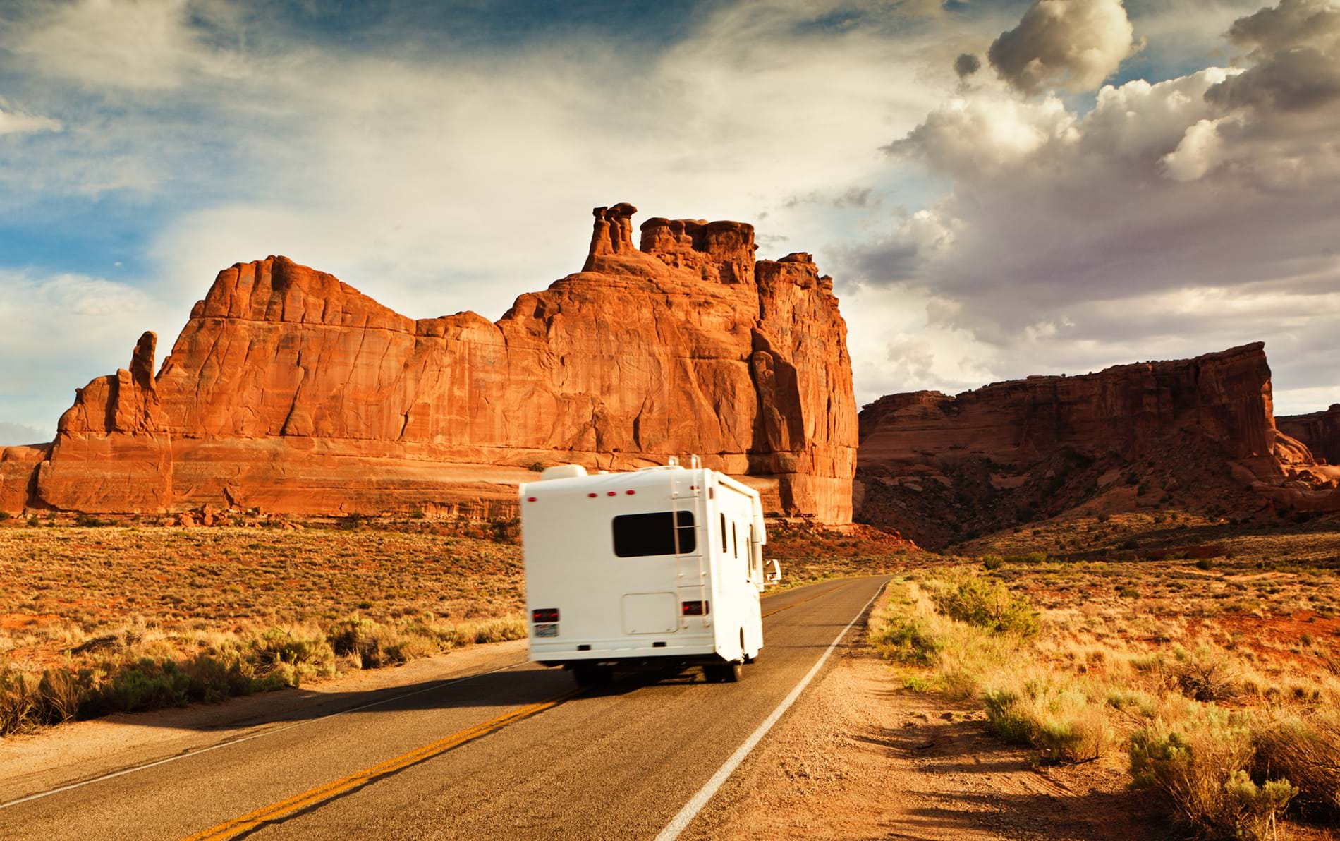 RV driving down road through desert