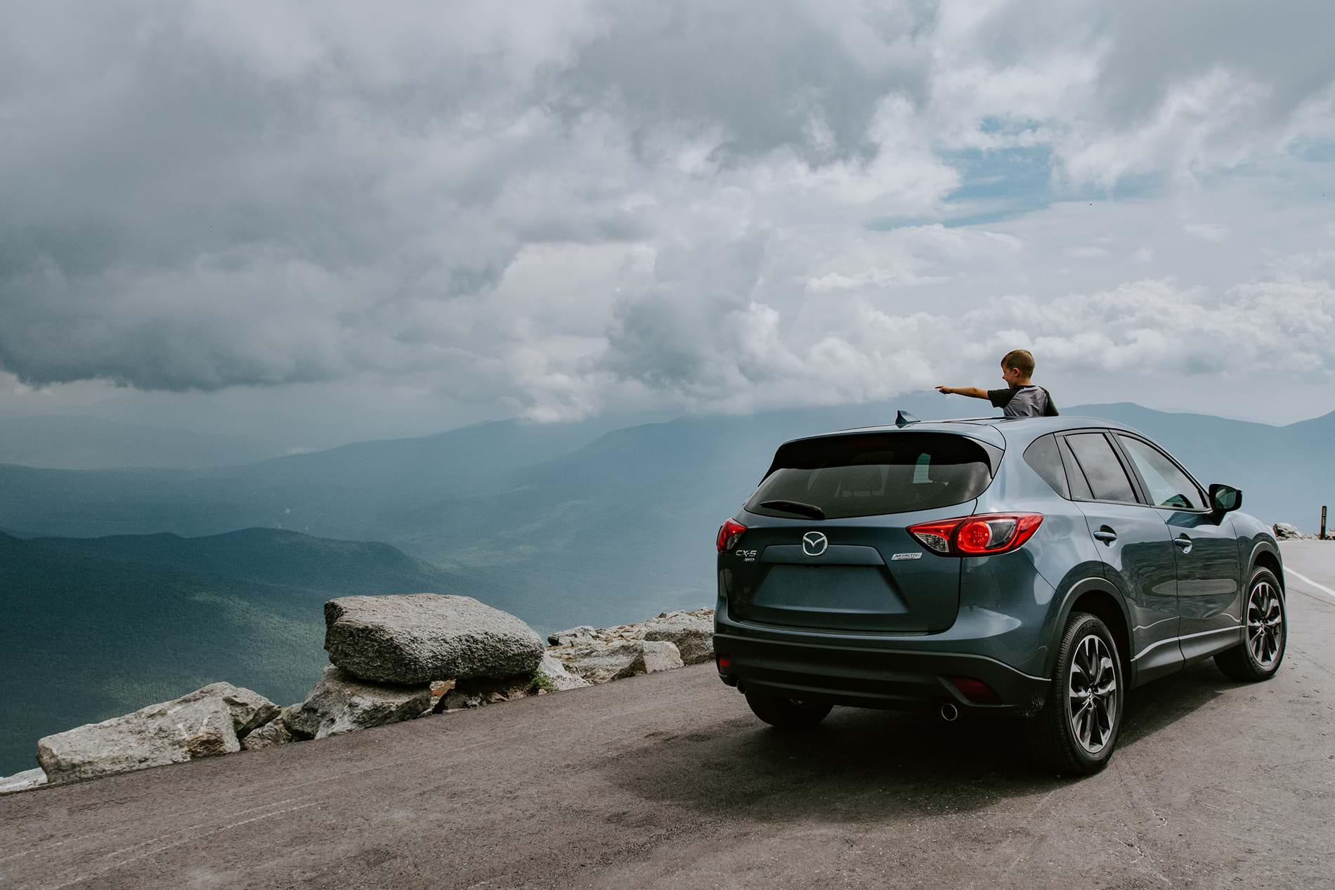 Grey SUV parked on road overlooking large valley