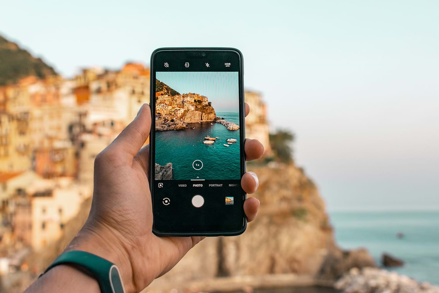 Phone taking picture of boats in water near coastal town