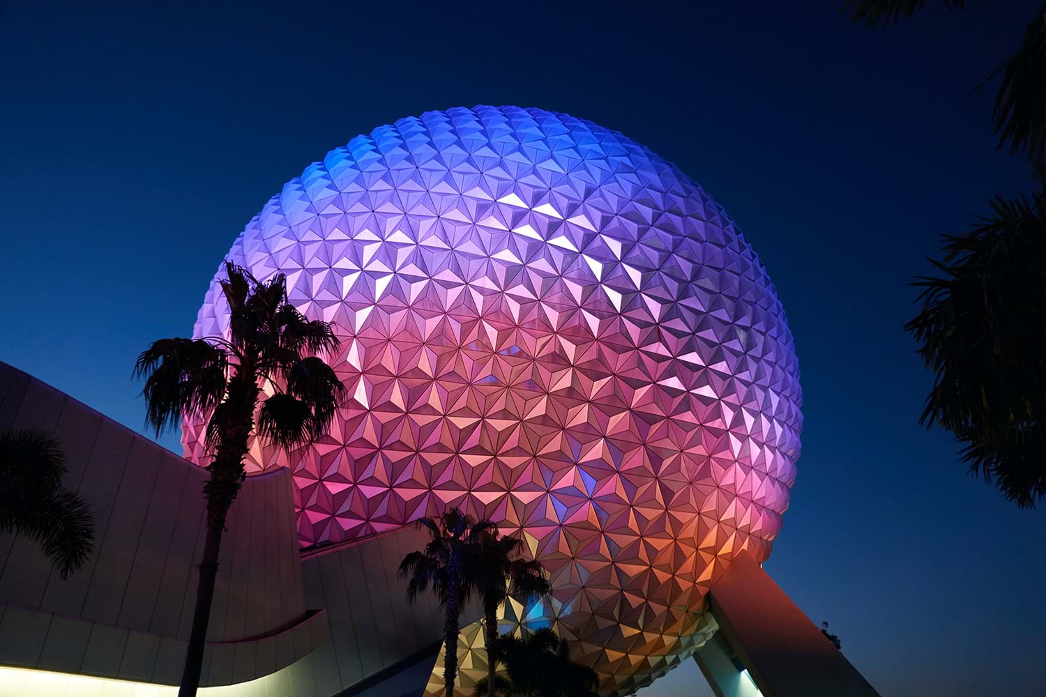 Epcot sphere lit by colorful lights at night