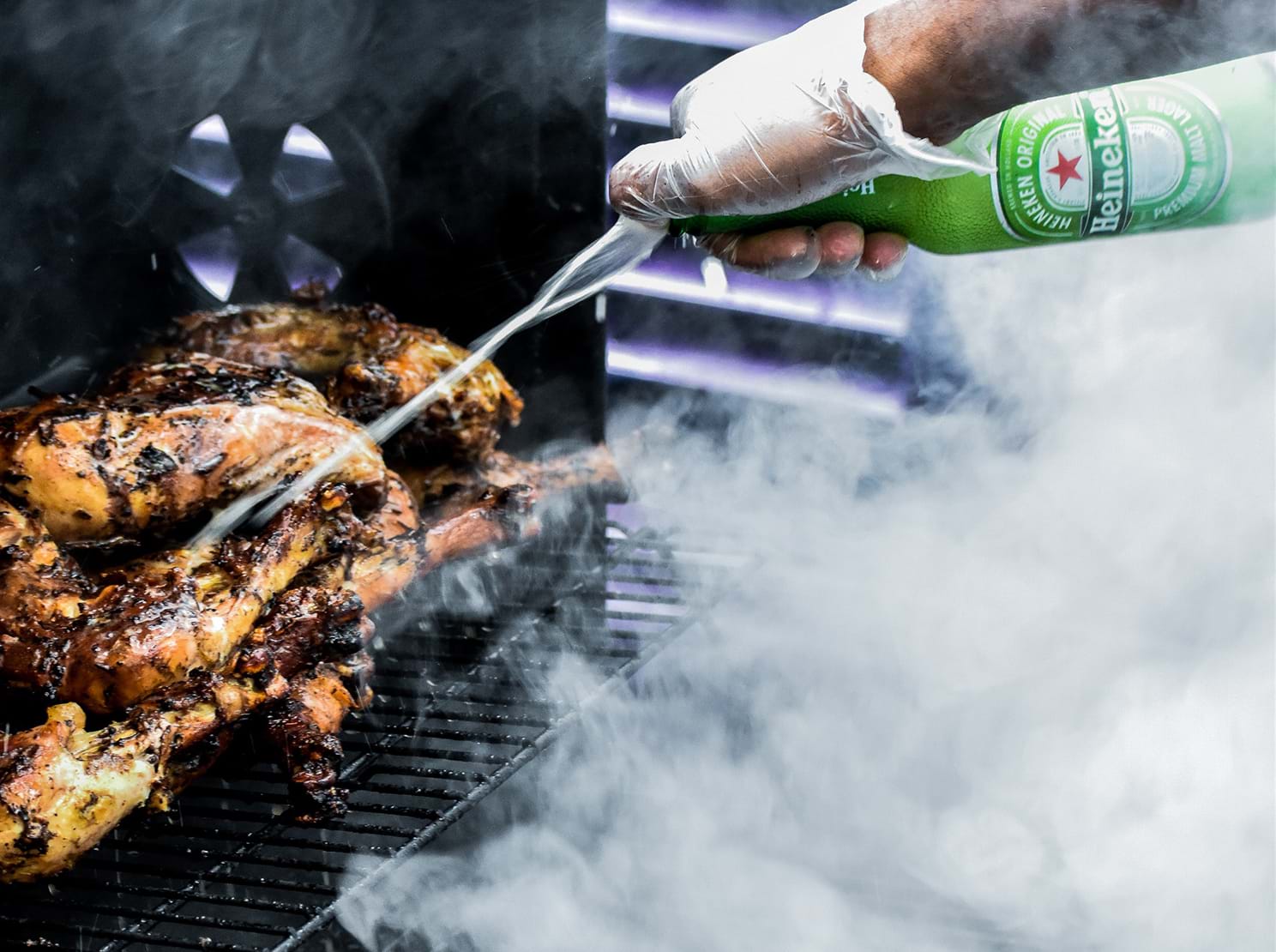 Pouring beer on chicken being grilled